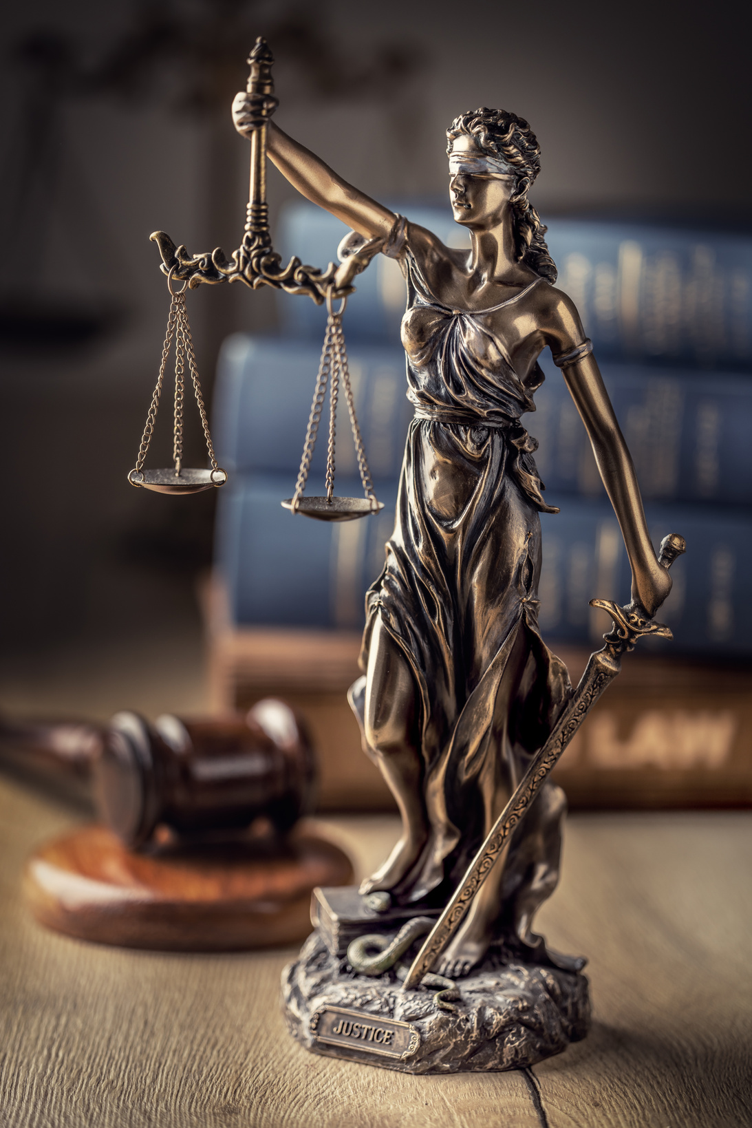 Statute of Justice and law books in the background.